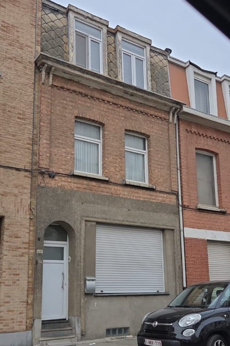 Gevel vóór de renovatie: verweerde baksteen en verouderde dakkapel